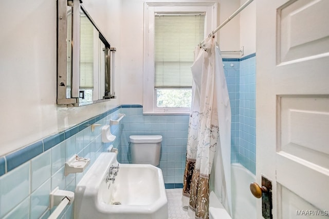 bathroom with toilet, shower / bath combo with shower curtain, and tile walls