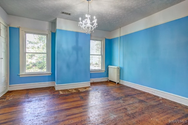 spare room with radiator, dark hardwood / wood-style flooring, a chandelier, and a textured ceiling