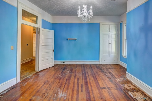 unfurnished room featuring hardwood / wood-style floors, a notable chandelier, and a textured ceiling