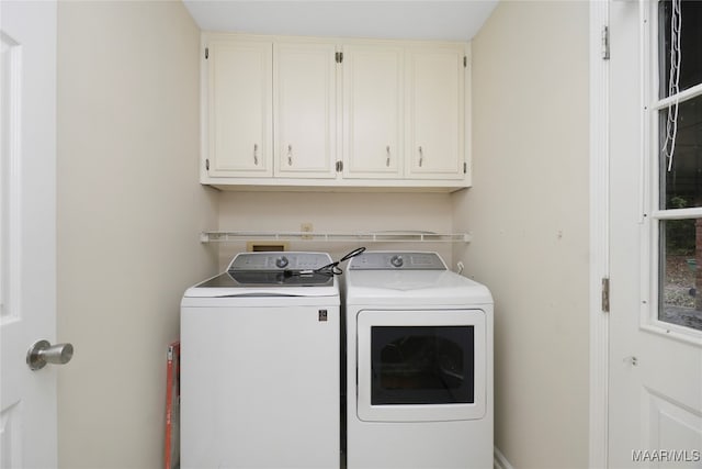 clothes washing area featuring cabinets and washer and clothes dryer