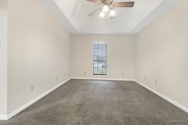 carpeted spare room with a raised ceiling and ceiling fan