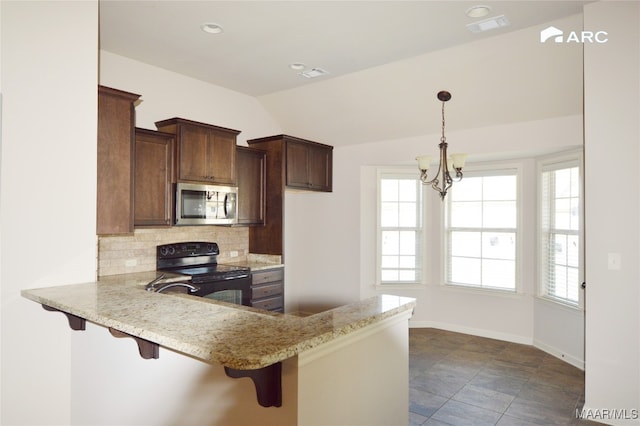 kitchen with kitchen peninsula, decorative backsplash, black / electric stove, and a breakfast bar area