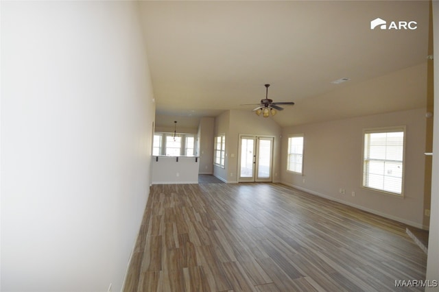 unfurnished living room with ceiling fan, a healthy amount of sunlight, lofted ceiling, and hardwood / wood-style flooring