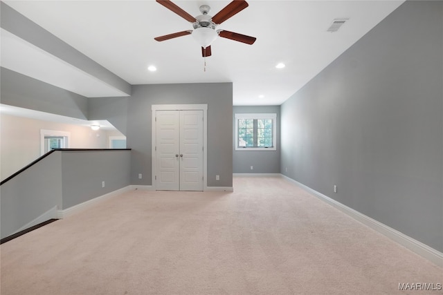 unfurnished bedroom featuring light carpet, a closet, and ceiling fan