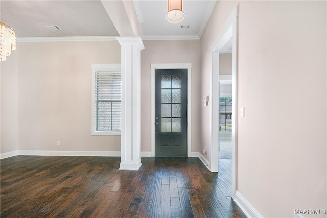 foyer with ornate columns, a notable chandelier, dark wood-type flooring, and crown molding