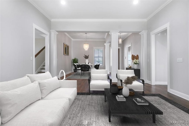 living room featuring a notable chandelier, dark hardwood / wood-style floors, ornate columns, and crown molding