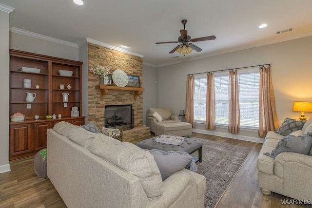 living room featuring dark hardwood / wood-style floors, a stone fireplace, ceiling fan, and ornamental molding