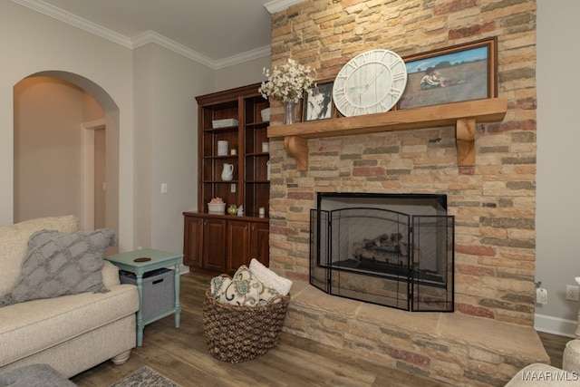 living room with a stone fireplace, crown molding, and hardwood / wood-style floors