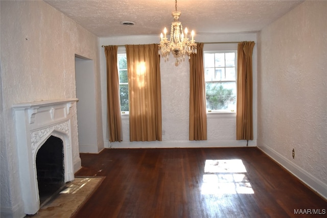 unfurnished living room featuring dark wood-type flooring, a textured ceiling, and an inviting chandelier