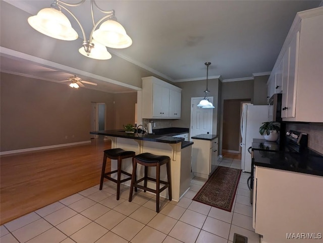 106 Crown Ridge Dr, Selma, AL 36701 - kitchen featuring dark countertops, white cabinets, a peninsula, light tile patterned floors, and ornamental molding