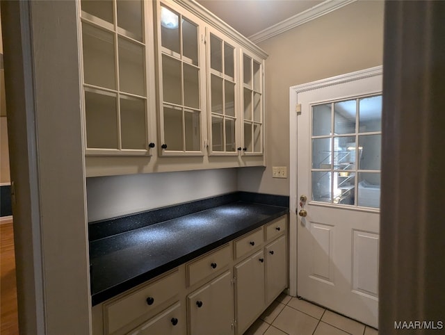 bar with light tile patterned flooring, white cabinetry, and crown molding