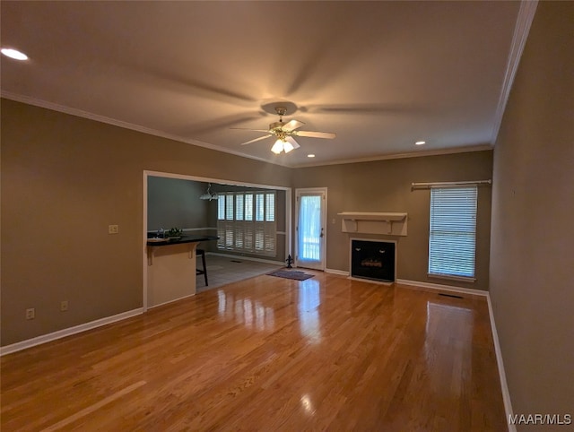 unfurnished living room with wood-type flooring, ceiling fan, and crown molding