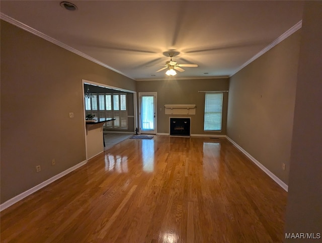 unfurnished living room featuring hardwood / wood-style floors, ceiling fan, and crown molding