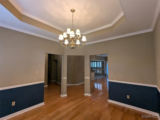 unfurnished dining area with hardwood / wood-style floors, a notable chandelier, a raised ceiling, and crown molding