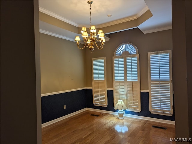 spare room with hardwood / wood-style floors, ornamental molding, and a notable chandelier