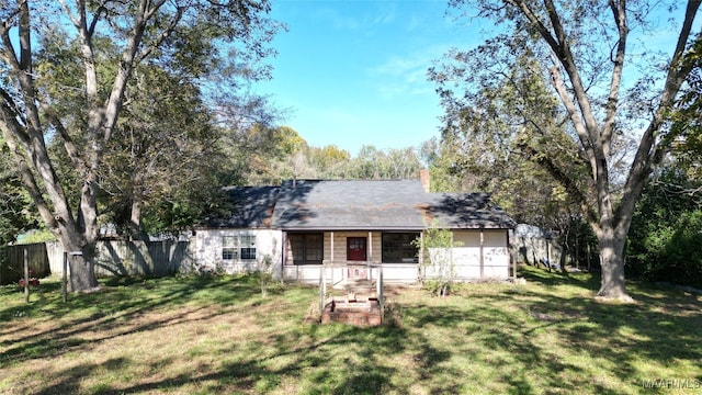 rear view of house featuring a lawn and a porch