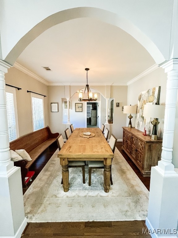 dining room with hardwood / wood-style flooring, ornamental molding, and an inviting chandelier