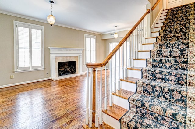 stairway featuring a wealth of natural light, crown molding, and wood finished floors