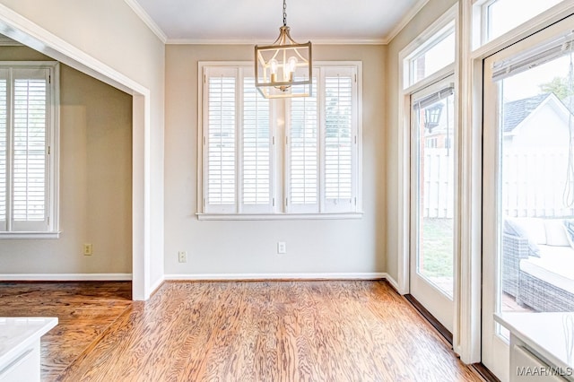 unfurnished dining area featuring ornamental molding, a wealth of natural light, baseboards, and light wood finished floors