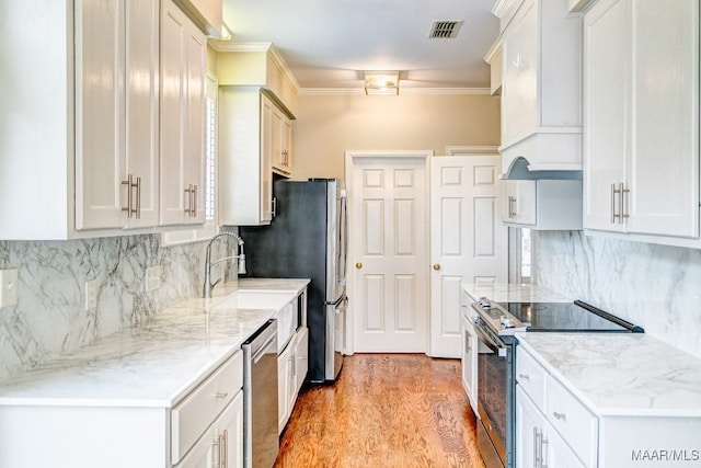 kitchen with stainless steel appliances, visible vents, light wood-style floors, custom range hood, and crown molding