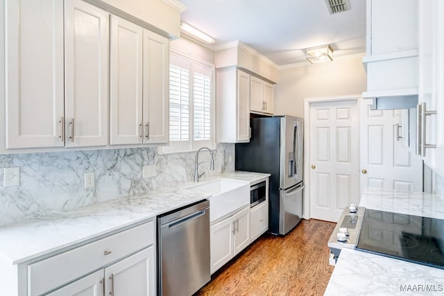 kitchen with visible vents, backsplash, appliances with stainless steel finishes, ornamental molding, and a sink