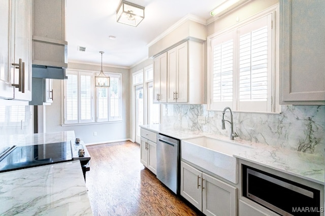 kitchen with light stone counters, a sink, ornamental molding, appliances with stainless steel finishes, and tasteful backsplash