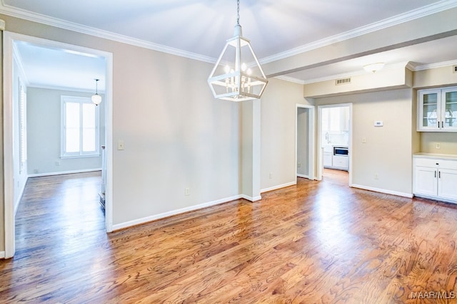 unfurnished dining area featuring ornamental molding, wood finished floors, visible vents, and baseboards