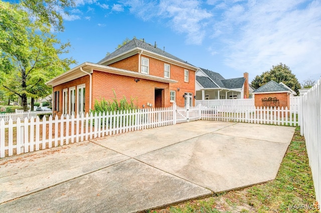 exterior space featuring a patio, brick siding, and a fenced front yard