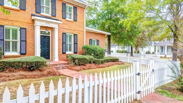 view of front of property with a fenced front yard, a gate, and brick siding