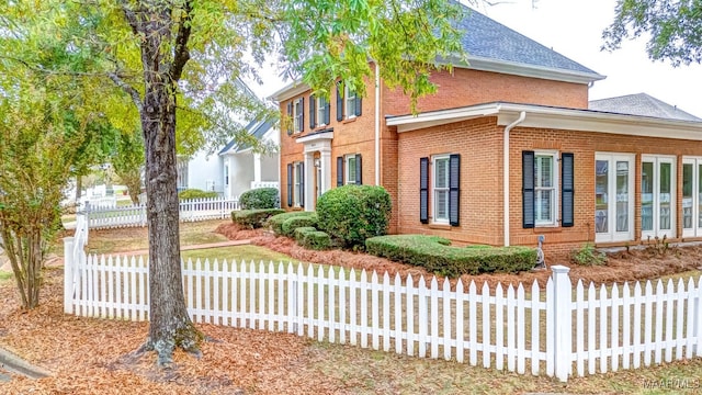 view of property exterior with brick siding and fence