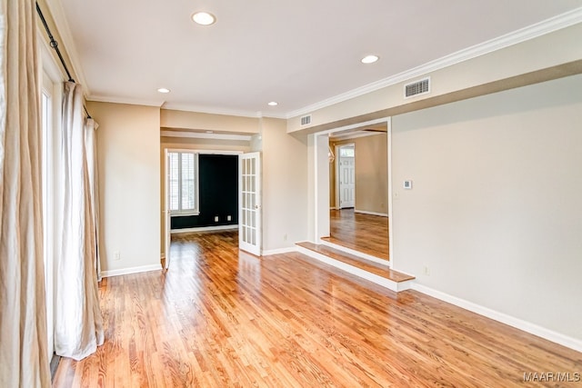 spare room with baseboards, visible vents, crown molding, and light wood finished floors