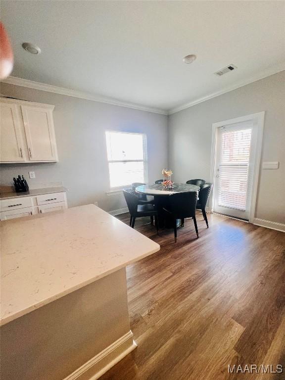 dining area featuring hardwood / wood-style flooring, ornamental molding, and a wealth of natural light