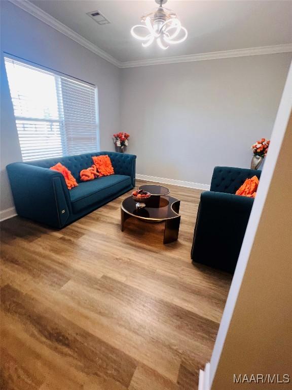 living room with an inviting chandelier, crown molding, and wood-type flooring