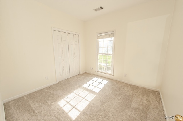 unfurnished bedroom with light colored carpet and a closet