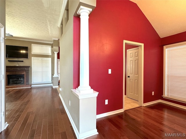 hall with wood-type flooring, decorative columns, a textured ceiling, and vaulted ceiling