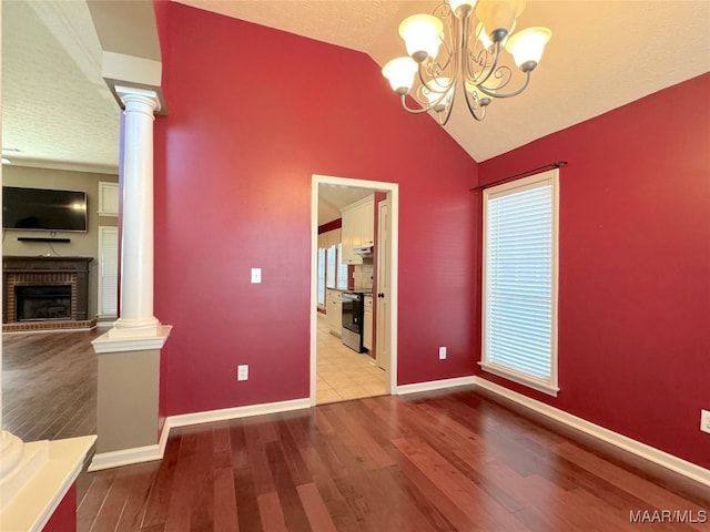 unfurnished dining area with hardwood / wood-style flooring, a fireplace, and ornate columns