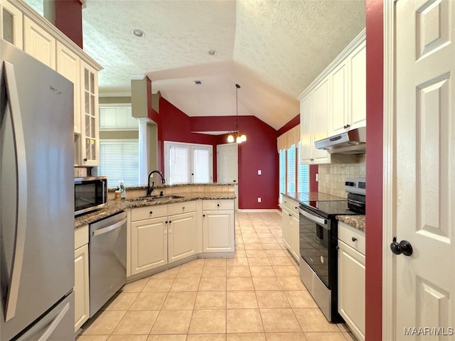 kitchen with stone counters, appliances with stainless steel finishes, sink, and pendant lighting