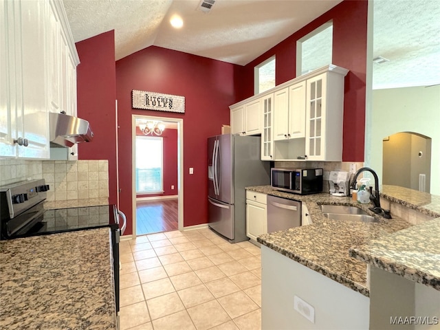 kitchen featuring appliances with stainless steel finishes, sink, white cabinets, light tile patterned floors, and kitchen peninsula