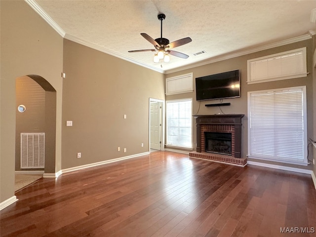 unfurnished living room featuring crown molding, ceiling fan, hardwood / wood-style floors, a fireplace, and a textured ceiling