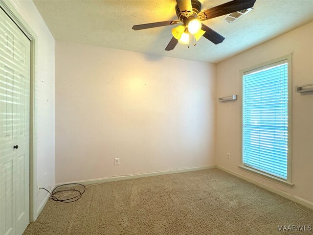 spare room with ceiling fan, a textured ceiling, and carpet flooring