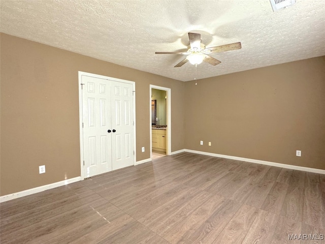 unfurnished bedroom featuring hardwood / wood-style flooring, a closet, and a textured ceiling