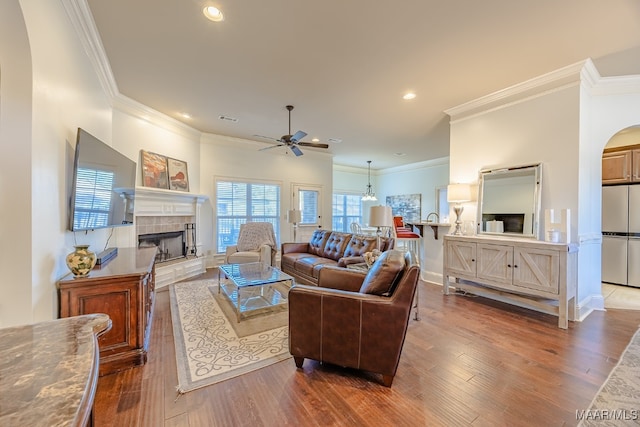 living room featuring ceiling fan, dark hardwood / wood-style flooring, crown molding, and a tile fireplace