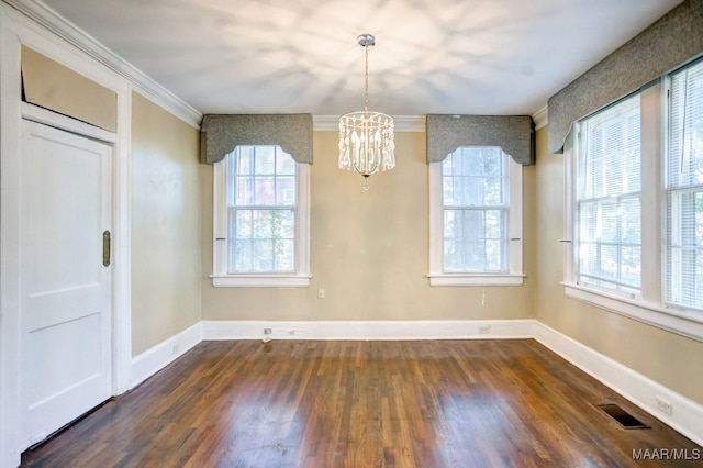 unfurnished dining area featuring crown molding, dark hardwood / wood-style floors, and an inviting chandelier