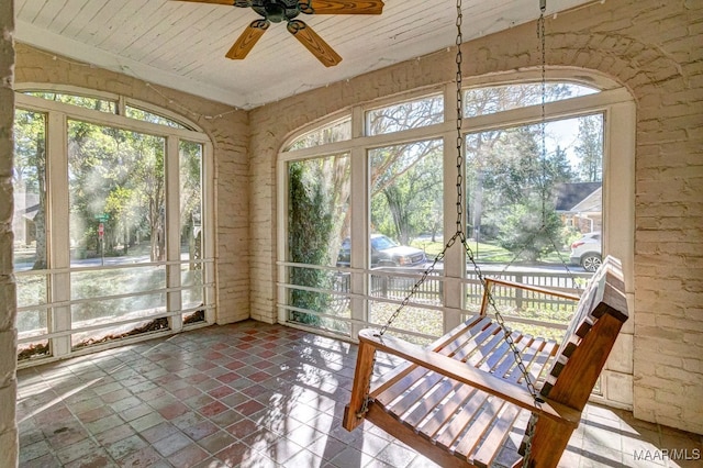 unfurnished sunroom featuring ceiling fan, plenty of natural light, and wood ceiling