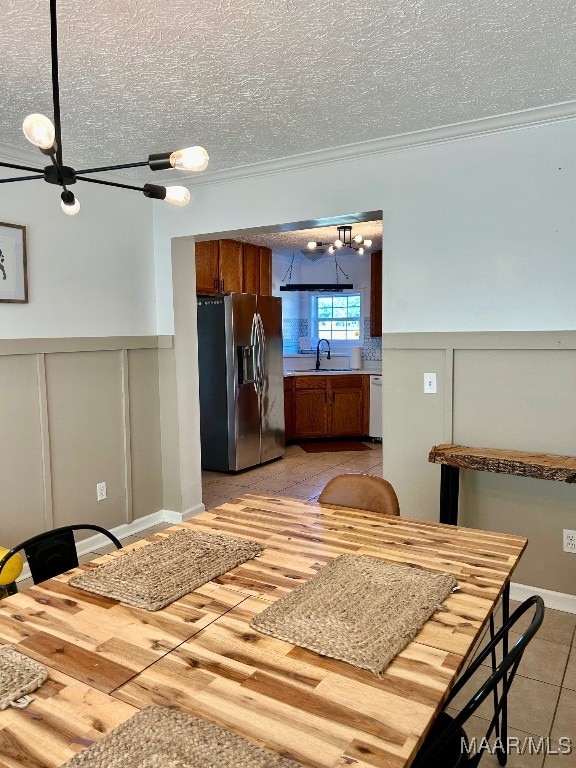 kitchen with a textured ceiling, sink, stainless steel appliances, and an inviting chandelier