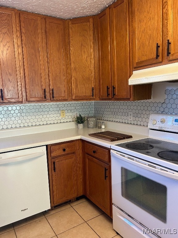 kitchen featuring white appliances, backsplash, and light tile patterned floors