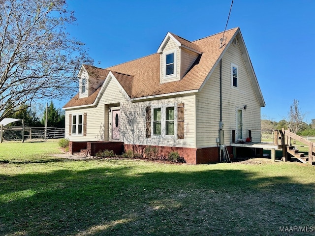 back of property with a shingled roof, fence, and a yard