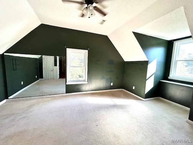 bonus room featuring carpet flooring, a textured ceiling, vaulted ceiling, and ceiling fan