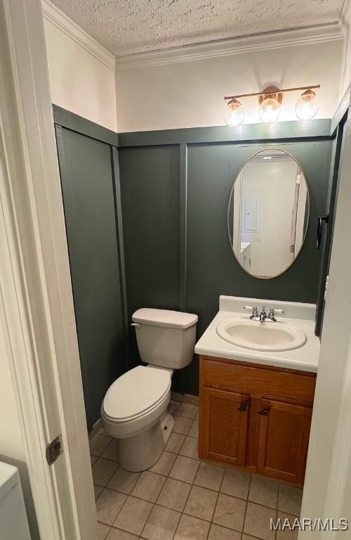 bathroom with vanity, crown molding, tile patterned flooring, toilet, and a textured ceiling