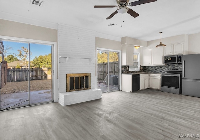 kitchen featuring appliances with stainless steel finishes, tasteful backsplash, decorative light fixtures, hardwood / wood-style flooring, and white cabinets